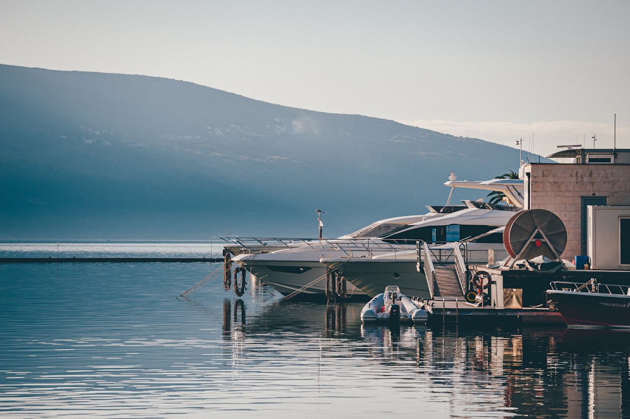 Home Elegant yachts docked in the serene waters of Tivat marina, Montenegro, with scenic mountain views.